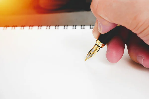 Pluma estilográfica con la mano sosteniendo la escritura en blanco cuaderno para el concepto de firma — Foto de Stock