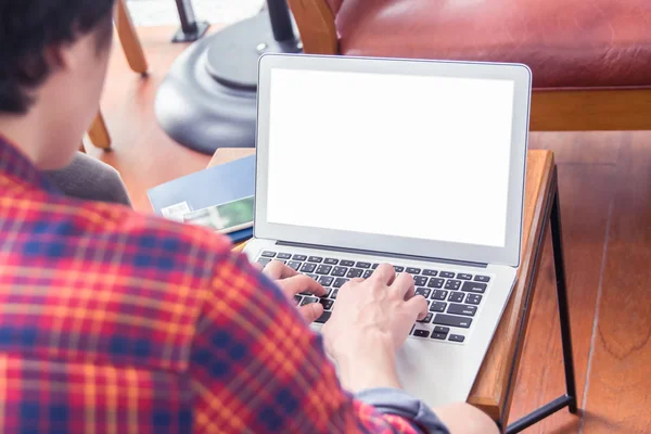 Young hands keyboarding on laptop with white blank screen while sitting at the wooden table in cafe or coffee shop — Stock Photo, Image