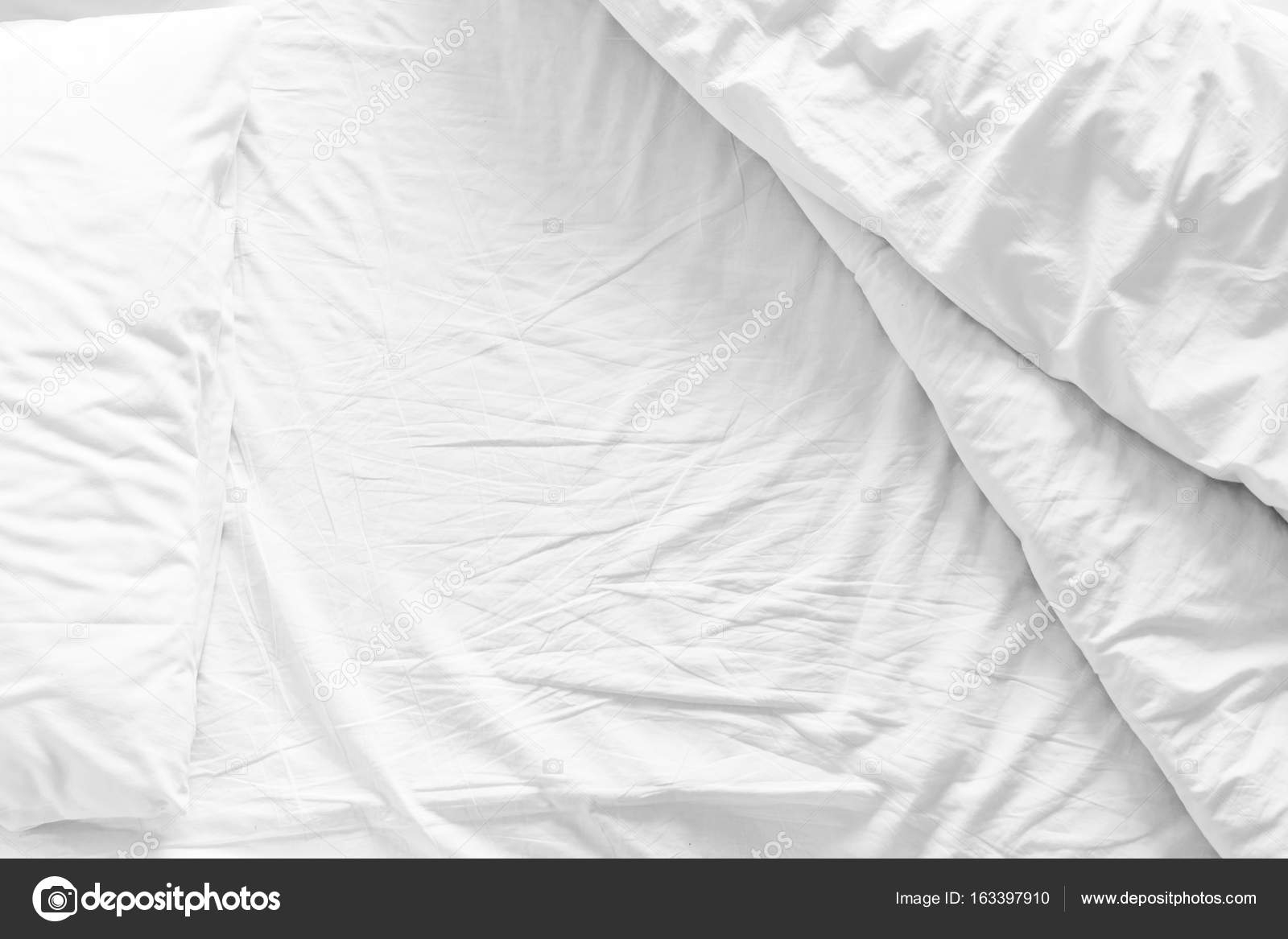 Unmade bed with crumpled bed sheet, a blanket and pillows after comfort