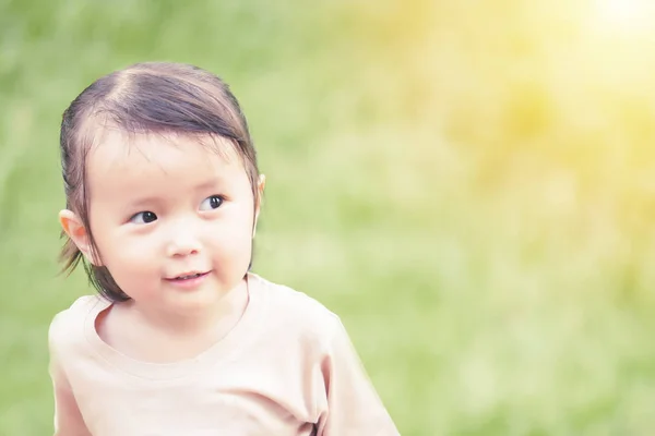 Retrato de niña jugando en el jardín verde con tono cálido y enfoque suave, bebé asiático — Foto de Stock