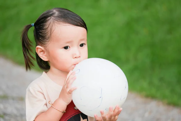 Blowing Up ballon: Close-up portret van meisje opblazen van een ballon in de groene tuin — Stockfoto