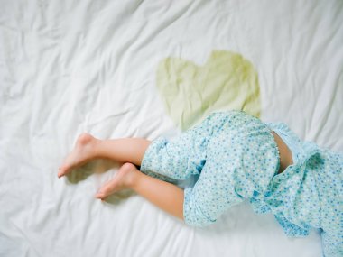 Bedwetting: Bir yatak, küçük kız ayak ve sidik çarşaf, çocuk geliştirme kavramı, içinde çocuk işerim ıslak yatakta odak seçili.