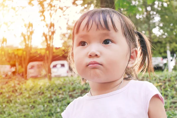 Portret van een klein meisje boos gezicht spelen in de groene tuin met warme toon en soft focus ondervraagt Aziatische baby — Stockfoto