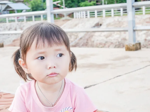 Portret van een klein meisje boos gezicht spelen in het park en de soft focus ondervraagt Aziatische baby — Stockfoto