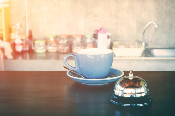 Dzwon i gorący coffee cup na kawiarnia licznik do alertu lub wark się koncepcja. — Zdjęcie stockowe