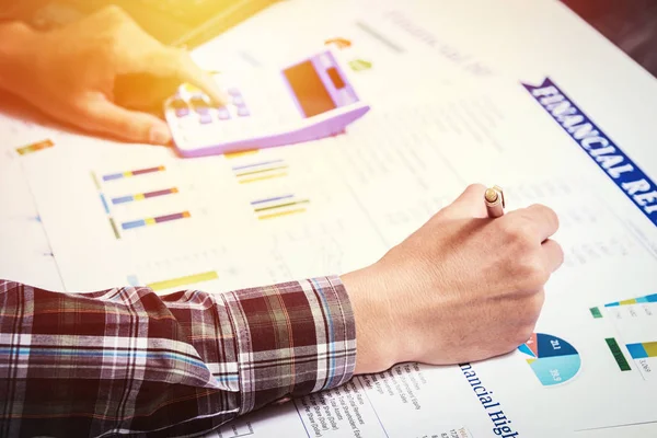 business finance accounting concept: business man hand using calculator and finance sheet report analysis on office desk