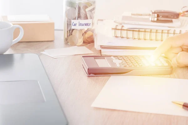 Concept d'assurance auto : homme utilisant la calculatrice sur le bureau avec pièce de monnaie dans l'épargne bancaire avec étiquette d'assurance auto — Photo