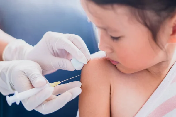 Niño pequeño que se inyecta, primer plano médico que inyecta la vacuna al brazo de una niña asiática en el hospital salud y concepto médico, 4-6 años de edad — Foto de Stock