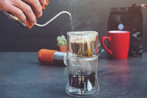 드립 브루 커피 카페인 필터 맛 머그 컵. 사람은 뜨거운 물을 붓고, 탁자 위에 걸러낸 커피 투명 한 유리 방울 기계를 준비 한다. 증기 — 스톡 사진