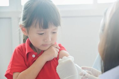 Asyalı küçük çocuk enjeksiyon oluyor, Doktor küçük kız aşısının koluna aşı enjekte ediyor bağışıklık, sağlık ve tıbbi konsept için klinik hastanesinde, 4-6 yaş arası.