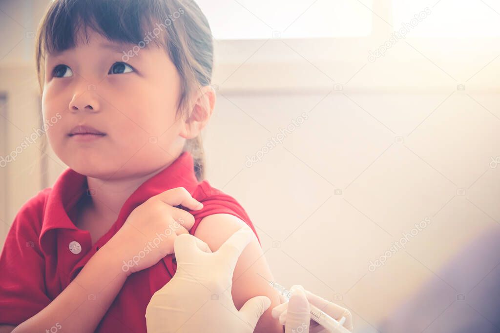 Asian Little child having Injection,Close-up Doctor injecting vaccination to arm of little girl vaccine injection in hospital for immunization afraid face and looking up ,health and medical concept.