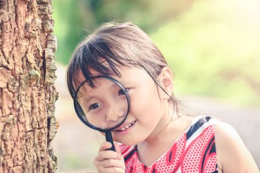 Büyüteçle bakan küçük kız ağaçtaki, çocukluktaki ve dünyadaki tüm böcekleri keşfediyor..