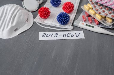 Medical face mask, stethoscope, pills and digital thermometer with inscription Wuhan coronavirus 2019-nCoV on the gray table background. Novel coronavirus 2019-nCoV concept.