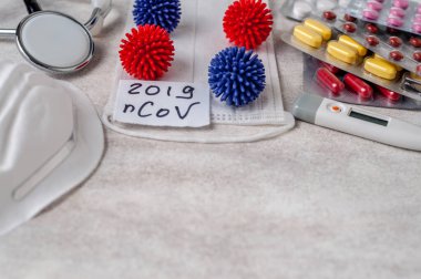 Medical face mask, stethoscope, pills and digital thermometer with inscription Wuhan coronavirus 2019-nCoV on the white table background. Novel coronavirus 2019-nCoV concept.