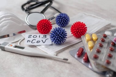 Medical face mask, stethoscope, pills and digital thermometer with inscription Wuhan coronavirus 2019-nCoV on the white table background. Novel coronavirus 2019-nCoV concept.