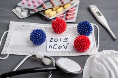 Medical face mask, stethoscope, pills and digital thermometer with inscription Wuhan coronavirus 2019-nCoV on the gray table background. Novel coronavirus 2019-nCoV concept.