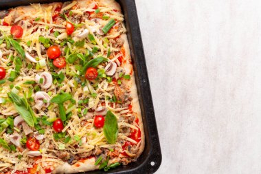 Mantarlı taze çiğ pizza, vişneli domates, Fesleğen ve Parmesan peyniri beyaz arka planda, fotokopi alanı olan dikdörtgen bir tavada. Pişirmeden önce ev yapımı pizza.