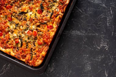 Mantarlı taze ve lezzetli bir pizza, kiraz domatesleri, dikdörtgen bir tavada Basil ve Parmesan fotokopi alanı ile birlikte. Ev yapımı pizza pişirme.