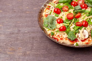 Mantarlı taze çiğ pizza, kiraz domatesli, Basil ve Parmesan yuvarlak bir tavada fotokopi alanı ile kahverengi bir arka planda. Pişirmeden önce ev yapımı pizza.