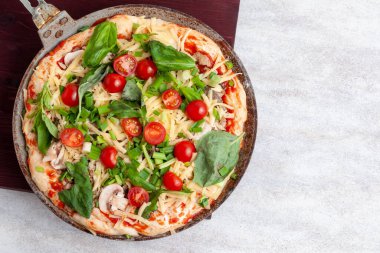 Mantarlı taze çiğ pizza, kiraz domatesli, Basil ve Parmesan yuvarlak bir tavada fotokopi alanı olan beyaz bir arka planda. Pişirmeden önce ev yapımı pizza.
