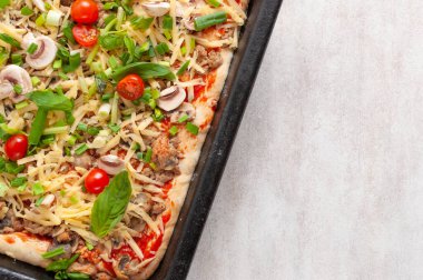 Mantarlı taze çiğ pizza, vişneli domates, Fesleğen ve Parmesan peyniri beyaz arka planda, fotokopi alanı olan dikdörtgen bir tavada. Pişirmeden önce ev yapımı pizza.