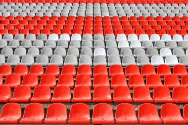 Arenanın tribünlerinde ya da konser salonundaki boş koltuklar. Seyirciler olmadan kırmızı ve beyaz stadyum koltukları. Spor ve kitlesel eğlence etkinliklerinin kaldırılması kavramı
