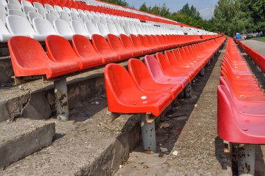 Arenanın tribünlerinde boş koltuklar. Seyirciler olmadan kırmızı ve beyaz stadyum koltukları. Spor ve kitlesel eğlence etkinliklerinin kaldırılması kavramı