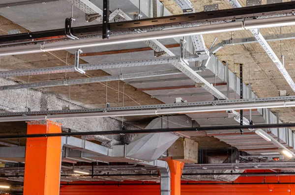 Ceiling insulation, ventilation system air ducts, fire extinguishing system pipes, electric cable channels under the ceiling of the Parking lot on the open ground floor of the building