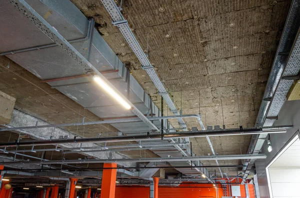 Ceiling insulation, ventilation system air ducts, fire extinguishing system pipes, electric cable channels under the ceiling of the Parking lot on the open ground floor of the building
