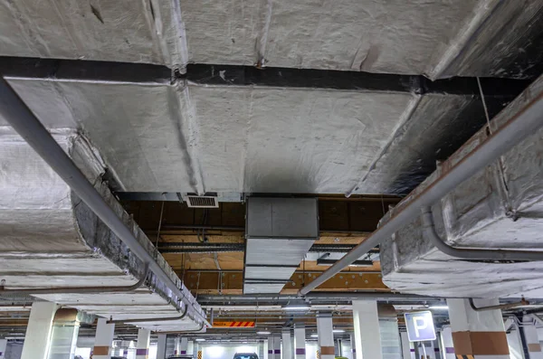 Ceiling insulation, ventilation system air ducts, fire extinguishing system pipes, electric cable channels under the ceiling of the Parking lot on the open ground floor of the building