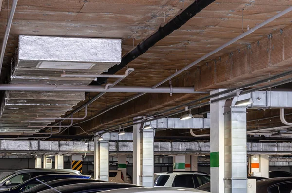 Ceiling insulation, ventilation system air ducts, fire extinguishing system pipes, electric cable channels under the ceiling of the Parking lot on the open ground floor of the building