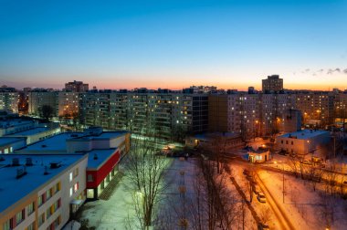 Kış kentsel manzarasının akşam manzarası. Günbatımında okullar, spor sahaları ve şehir blokları