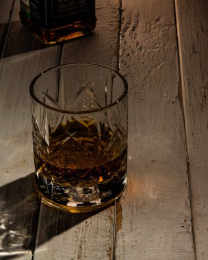 Şişe ve bir bardak viski. Arka planda.