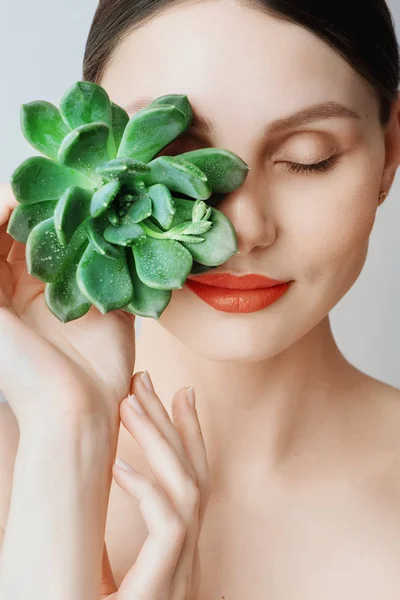 Portret van een mooie jonge brunette vrouw met groene blad in zijn hand in de studio, het concept van schoonheid en gezondheid — Stockfoto