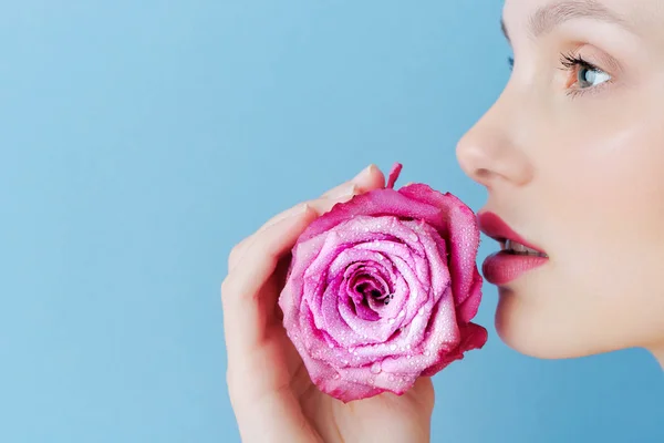 Portré egy szép barna lány, egy rózsaszín rózsa, kék háttérrel — Stock Fotó