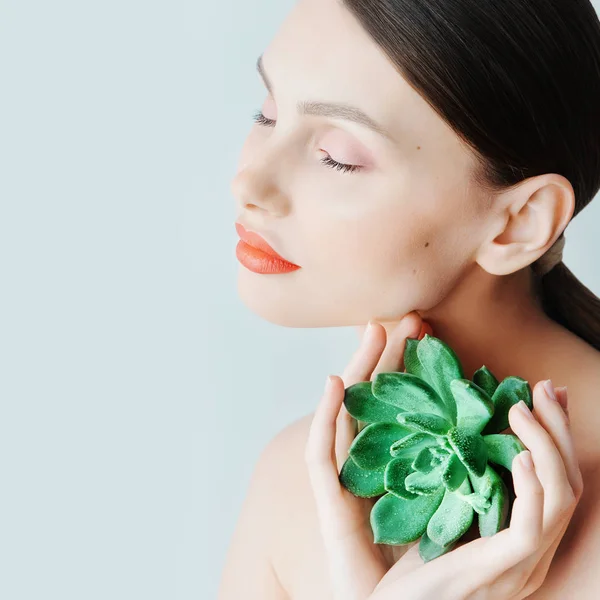 Portret van een mooie jonge brunette vrouw met groene blad in zijn hand in de studio, het concept van schoonheid en gezondheid — Stockfoto