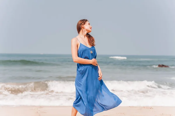 Güzel kız mavi elbiseli denizin yanında ayakta — Stok fotoğraf