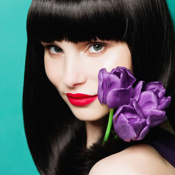 Portrait d'une belle fille brune avec une tulipe lilas sur fond bleu — Photo