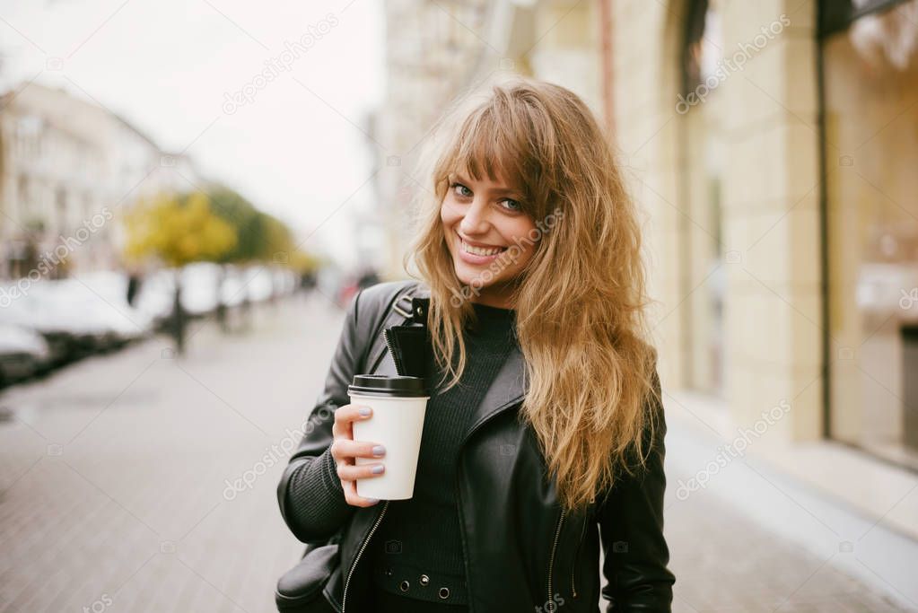 Portrait of a beautiful girl on the street, holding a paper cup