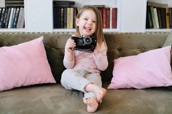 Een klein meisje zittend op een bed met een camera Rechtenvrije Stockafbeeldingen