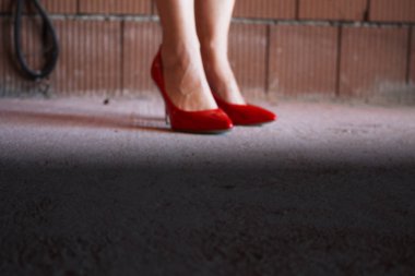 Bitmemiş bir evde kırmızı topuklu ayakkabı giyen kadın bacakları.