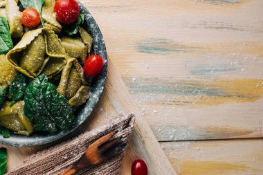 Eski ahşap bir masada domates, un, ıspanak, yumurta gibi taze malzemelerle çevrili ıspanaklı tortellini. Vejetaryen yemeği. kopyalama alanı