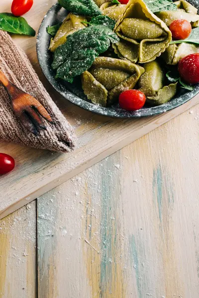 Eski ahşap bir masada domates, un, ıspanak, yumurta gibi taze malzemelerle çevrili ıspanaklı tortellini. Vejetaryen yemeği. kopyalama alanı