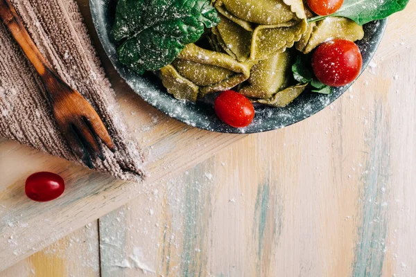 Eski ahşap bir masada domates, un, ıspanak, yumurta gibi taze malzemelerle çevrili ıspanaklı tortellini. Vejetaryen yemeği. kopyalama alanı