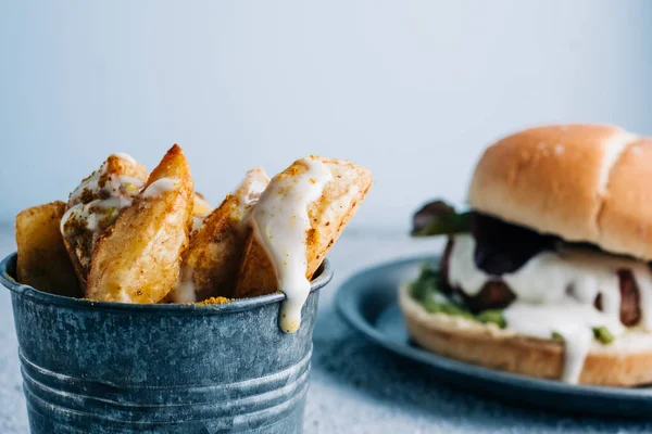 Metal kasede baharatlı patates kızartması ve arka planda hamburger. seçici odak
