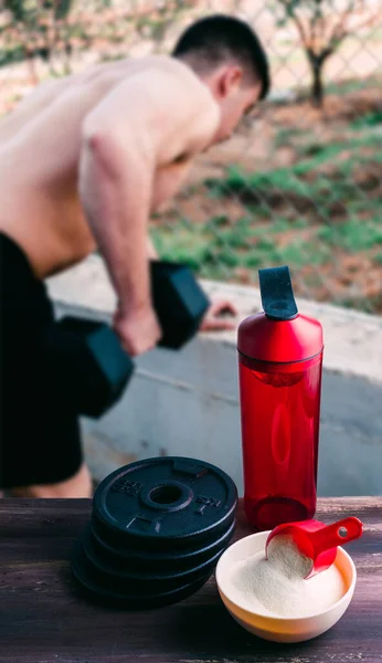 Protein shake Vanilla flavor accompanied by weights and sportsmen in the background