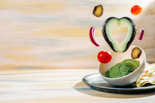 İçinde malzemeler yüzen ev yapımı guacamole kasesi. Klasik ahşap masa. Sağlıklı yemek.