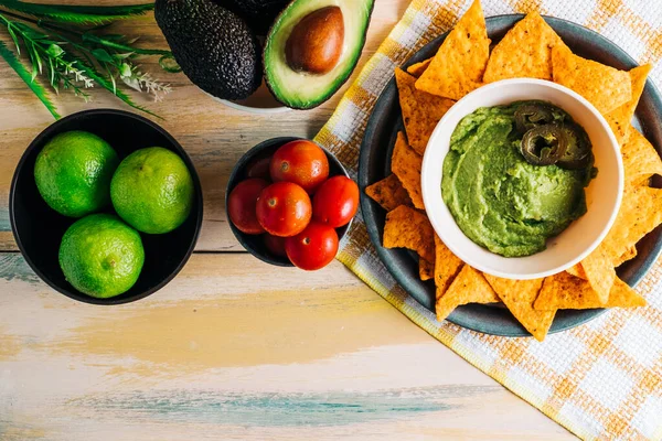 Antika ahşap masada taze malzemelerle birlikte nachos soslu guacamole kasesi. Uzayı kopyala Vejetaryen yemeği