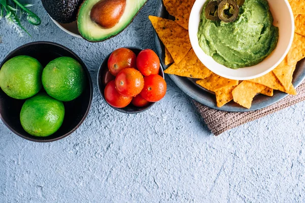 Domatesler, biberler, limonlar ve avokadolarla çevrili eski ahşap masada Meksika guacamole ile bir kase. Kopyalama alanı