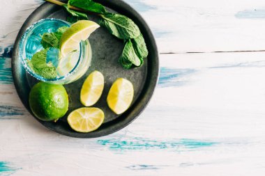 Limonlu içecek. Ev yapımı mojito. Etrafı limon, nane ve şekerle çevrili ahşap masa. Kopyalama alanı